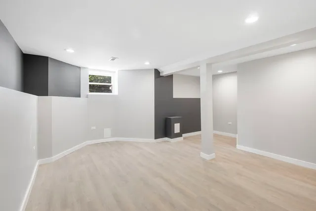 a view of an empty room with kitchen and a window