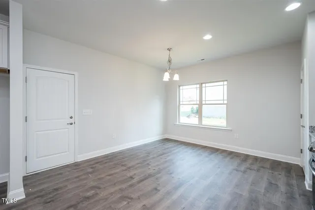 wooden floor in an empty room with a kitchen