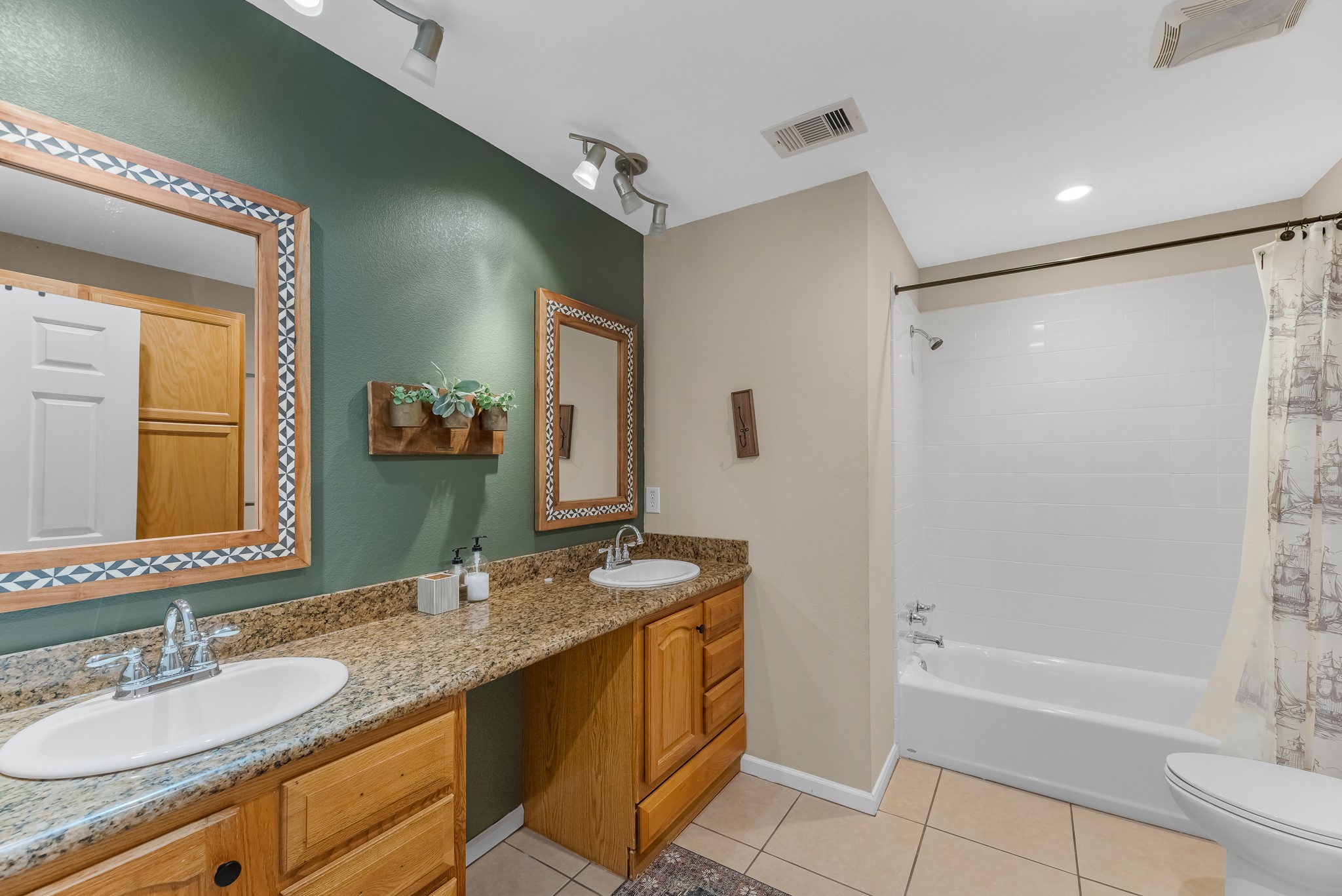 211 Captains Road Anahuac, TX 77514 - Photo 30 of 39 a bathroom with a granite countertop sink a mirror a bathtub and shower