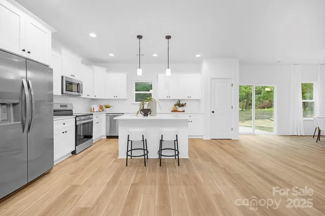 a kitchen with stainless steel appliances kitchen island granite countertop a refrigerator a stove a sink dishwasher with a dining table and chairs