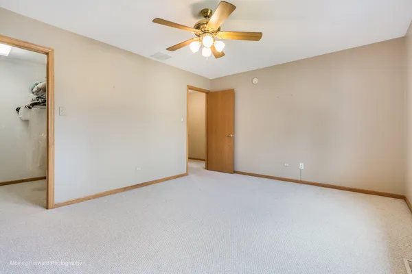 an empty room with a chandelier fan and windows
