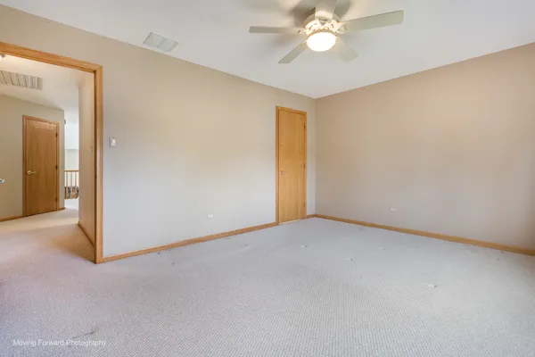 an empty room with a chandelier fan and a bathroom