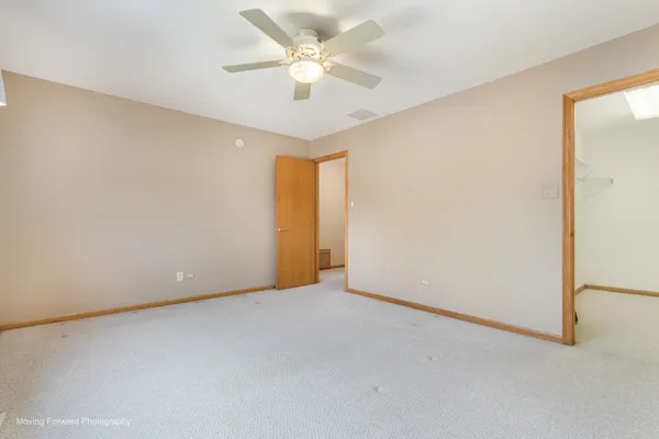 an empty room with a chandelier fan and windows