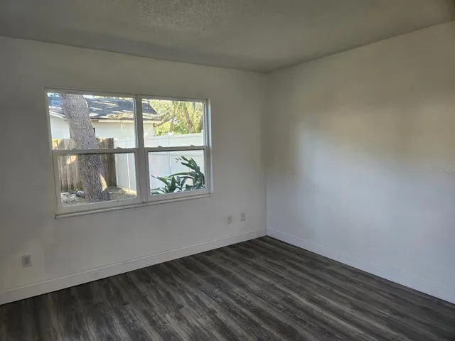 an empty room with wooden floor and window
