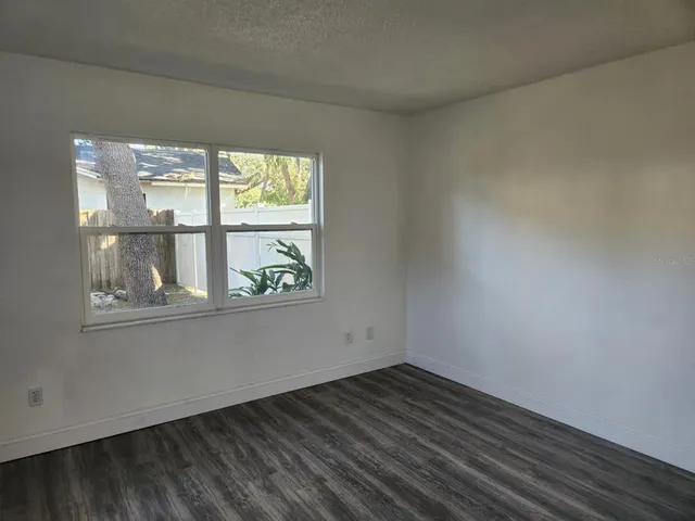 an empty room with wooden floor and window
