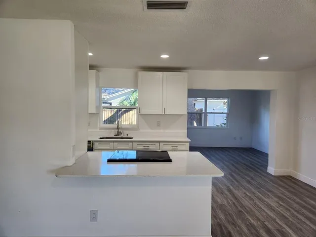 a kitchen with kitchen island a sink wooden floor and window
