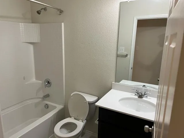 a bathroom with a bathtub shower sink vanity and toilet