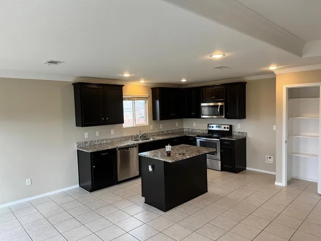 a kitchen with stainless steel appliances granite countertop a stove top oven a sink and a refrigerator