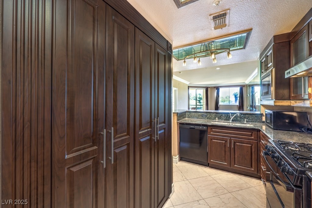 270 East Flamingo Road, Unit 115 Las Vegas, NV 89169 - Photo 11 of 29 Kitchen with a textured ceiling, black appliances, dark brown cabinets, light marble finish floors, and dark stone counters