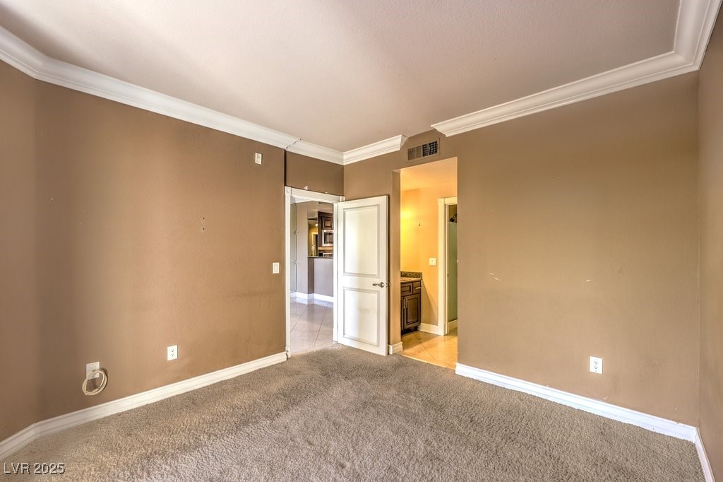 270 East Flamingo Road, Unit 115 Las Vegas, NV 89169 - Photo 17 of 29 Unfurnished bedroom with ornamental molding, light carpet, and connected bathroom