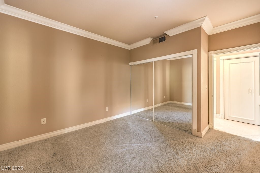 270 East Flamingo Road, Unit 115 Las Vegas, NV 89169 - Photo 21 of 29 Unfurnished bedroom featuring ornamental molding, carpet, and a closet