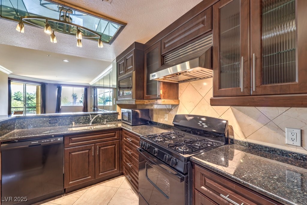 270 East Flamingo Road, Unit 115 Las Vegas, NV 89169 - Photo 10 of 29 Kitchen with dark brown cabinets, black appliances, dark stone countertops, crown molding, and a textured ceiling