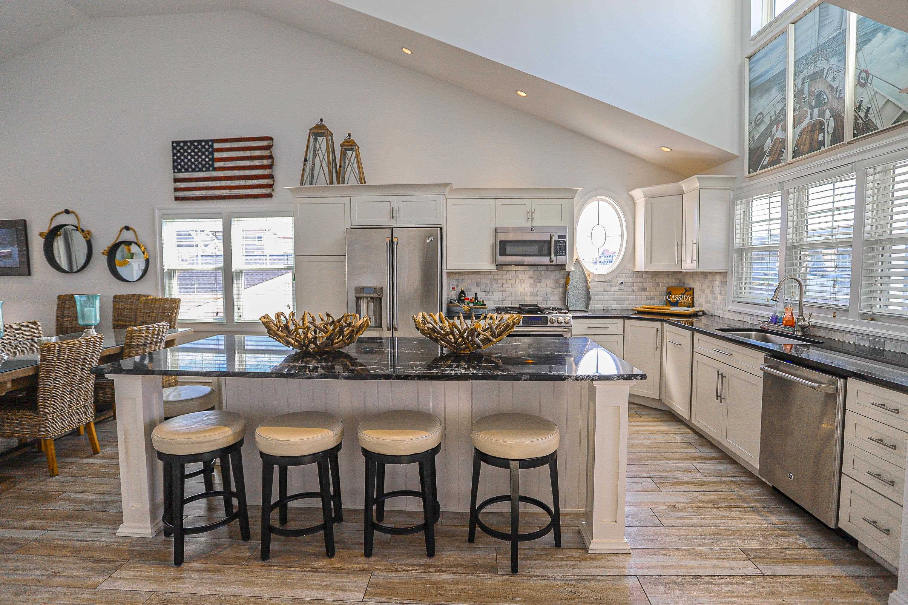 285 78th Street Avalon, NJ 08202 - Photo 6 of 48 a kitchen with stainless steel appliances kitchen island granite countertop a table chairs in it and wooden floors