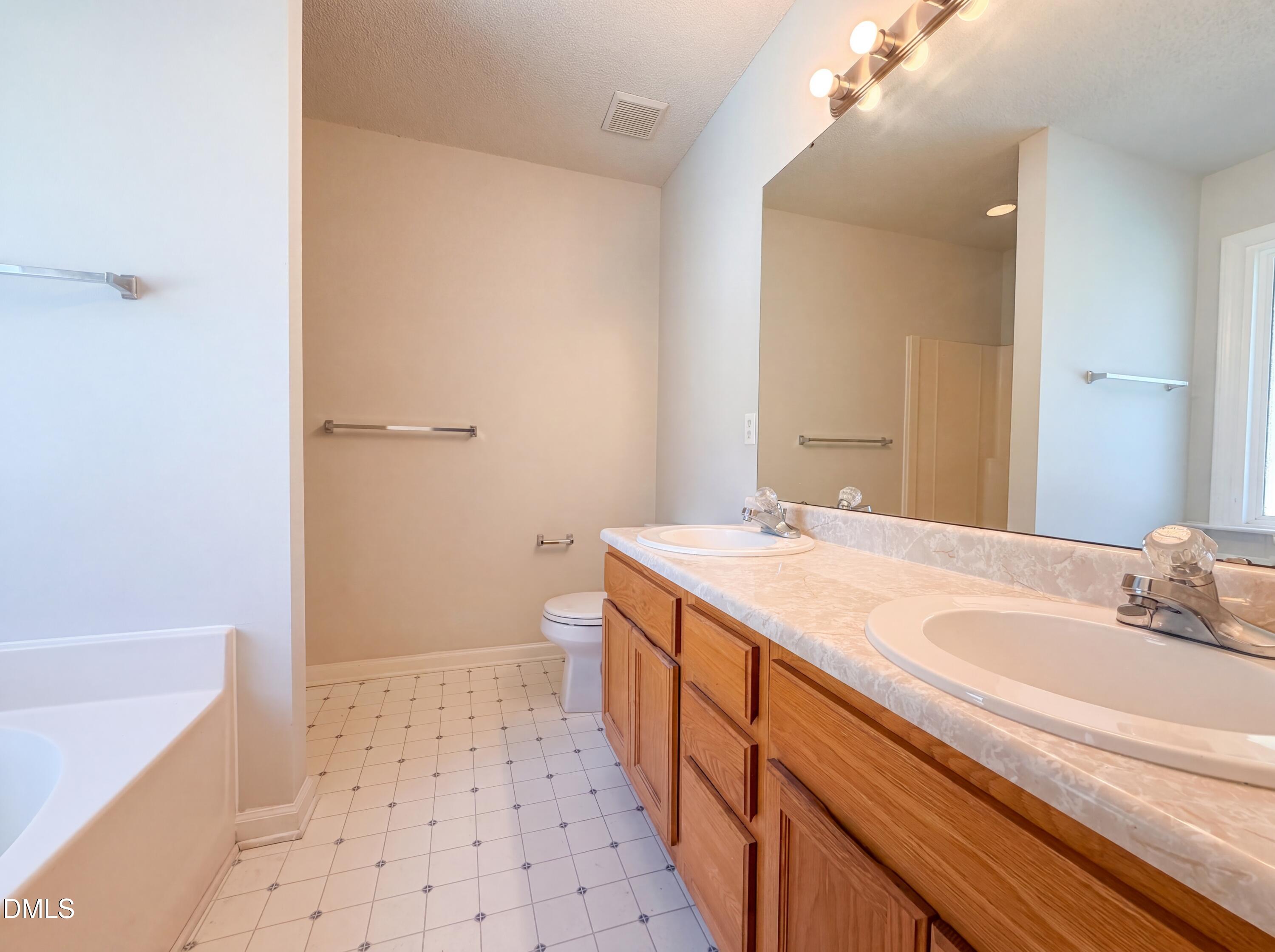 765 Trebor Drive Garner, NC 27529 - Photo 20 of 27 a spacious bathroom with a sink a toilet a shower and a mirror