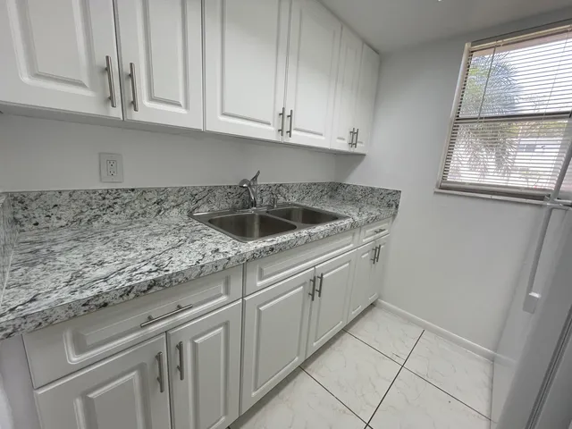 a kitchen with granite countertop white cabinets and a sink