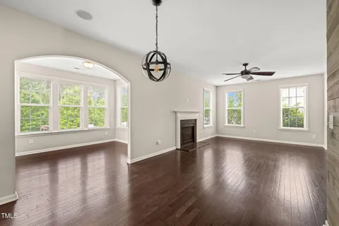 a view of an empty room with wooden floor fridge and a window