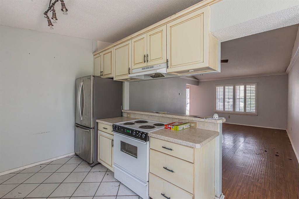 6504 Johnnie Street Watauga, TX 76148 - Photo 11 of 23 Kitchen area featuring cream cabinetry with dark hardware, a white electric range, and a stainless steel refrigerator