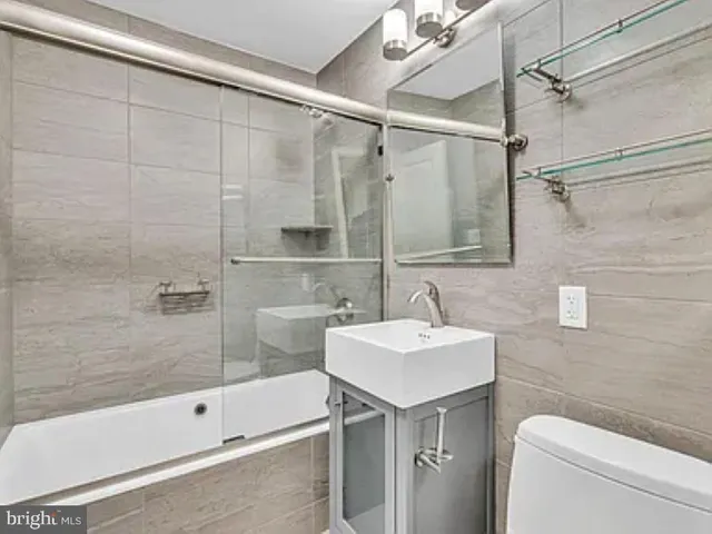 a bathroom with a sink and mirror with bathtub