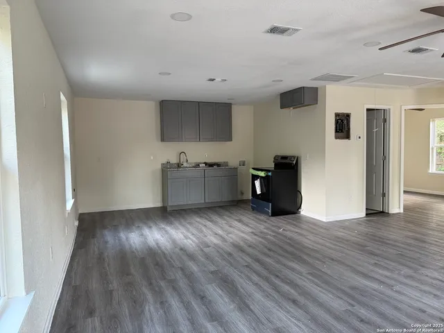 an empty room with wooden floor ceiling fan and windows