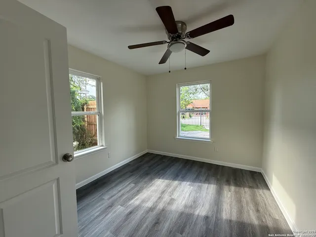 a view of an empty room with wooden floor and a window