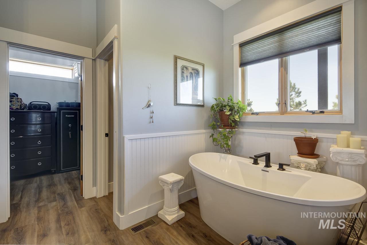 415 North Locust Grove Road Kuna, ID 83634 - Photo 26 of 49 Bathroom with wainscoting, a freestanding tub, and dark wood-style flooring