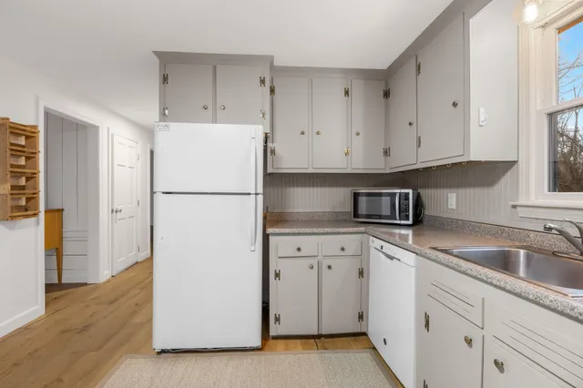 a kitchen with cabinets appliances and a wooden floor