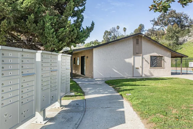 a white house with a small yard plants and large tree