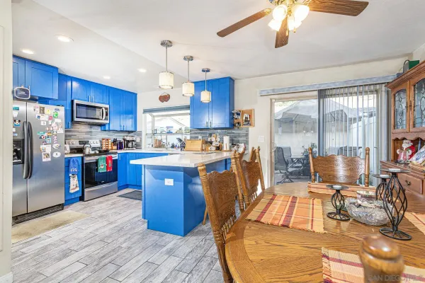 a kitchen with stainless steel appliances granite countertop a refrigerator a sink dishwasher a stove and a dining table with wooden floor