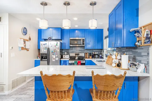 a kitchen with stainless steel appliances wooden floors wooden cabinets a dining table and chairs