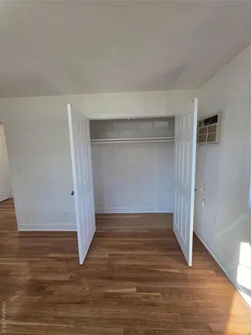 a view of an empty room with wooden floor and closet