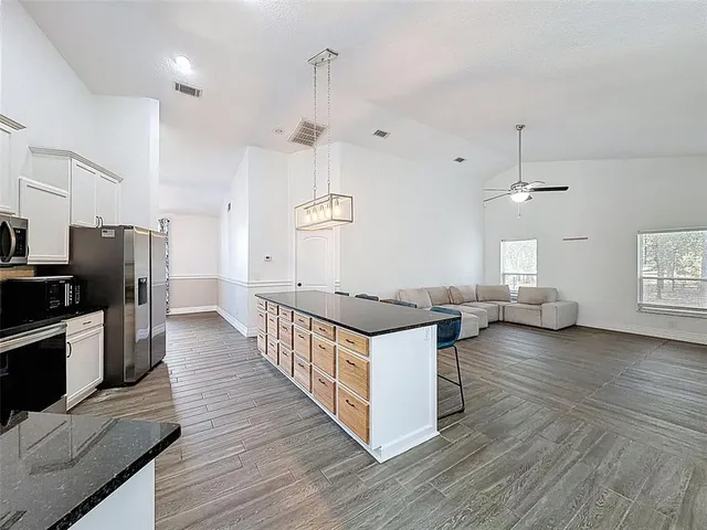 a view of a livingroom with a chandelier fan and a kitchen