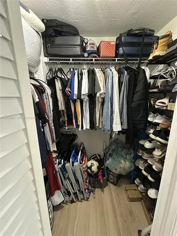 a view of walk in closet with clothes and shoes