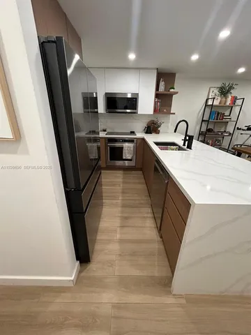 a large kitchen with stainless steel appliances wooden floor sink and stove