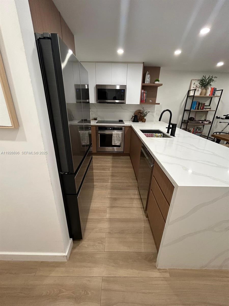 5838 Collins Avenue, Unit 11D Miami Beach, FL 33140 - Photo 8 of 24 a large kitchen with stainless steel appliances wooden floor sink and stove