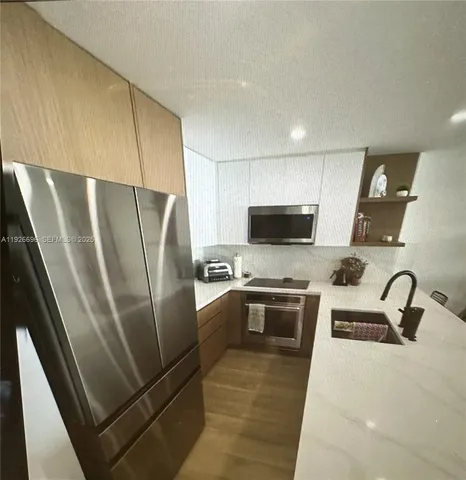a kitchen with stainless steel appliances a refrigerator a sink a stove a microwave and island