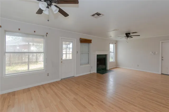 a view of empty room with wooden floor and fan