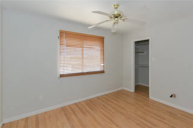 a view of empty room with wooden floor and fan