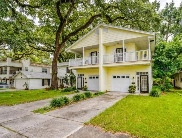 a view of a white house with a big yard and large trees