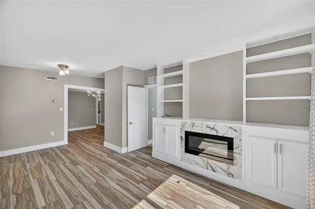 a view of kitchen and empty room with wooden floor
