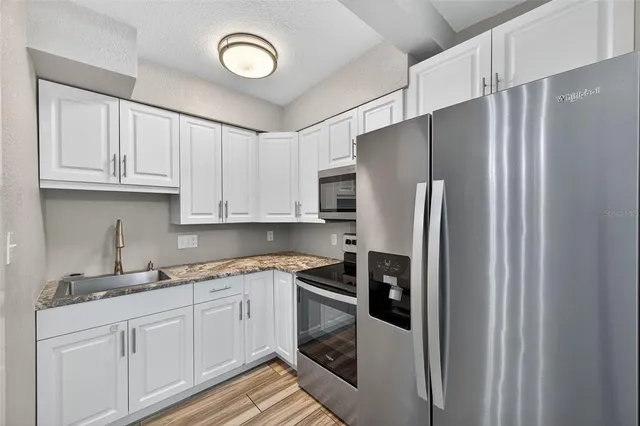 a kitchen with stainless steel appliances granite countertop a refrigerator sink and cabinets