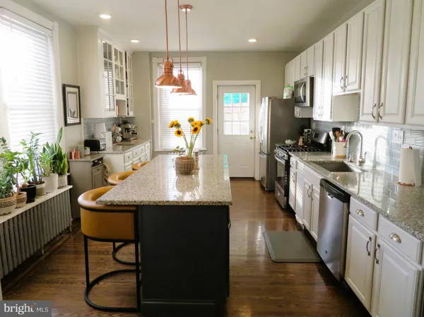 a kitchen with kitchen island granite countertop a sink a counter top space stainless steel appliances and cabinets