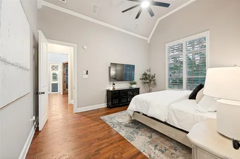 a bedroom with a bed a flat screen tv and a chandelier