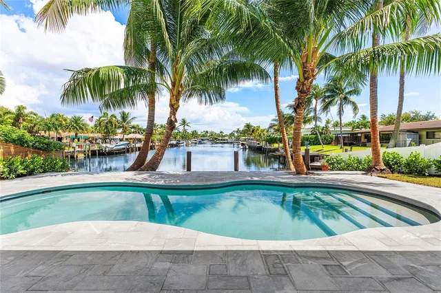 a view of a swimming pool with a lawn chairs and palm trees