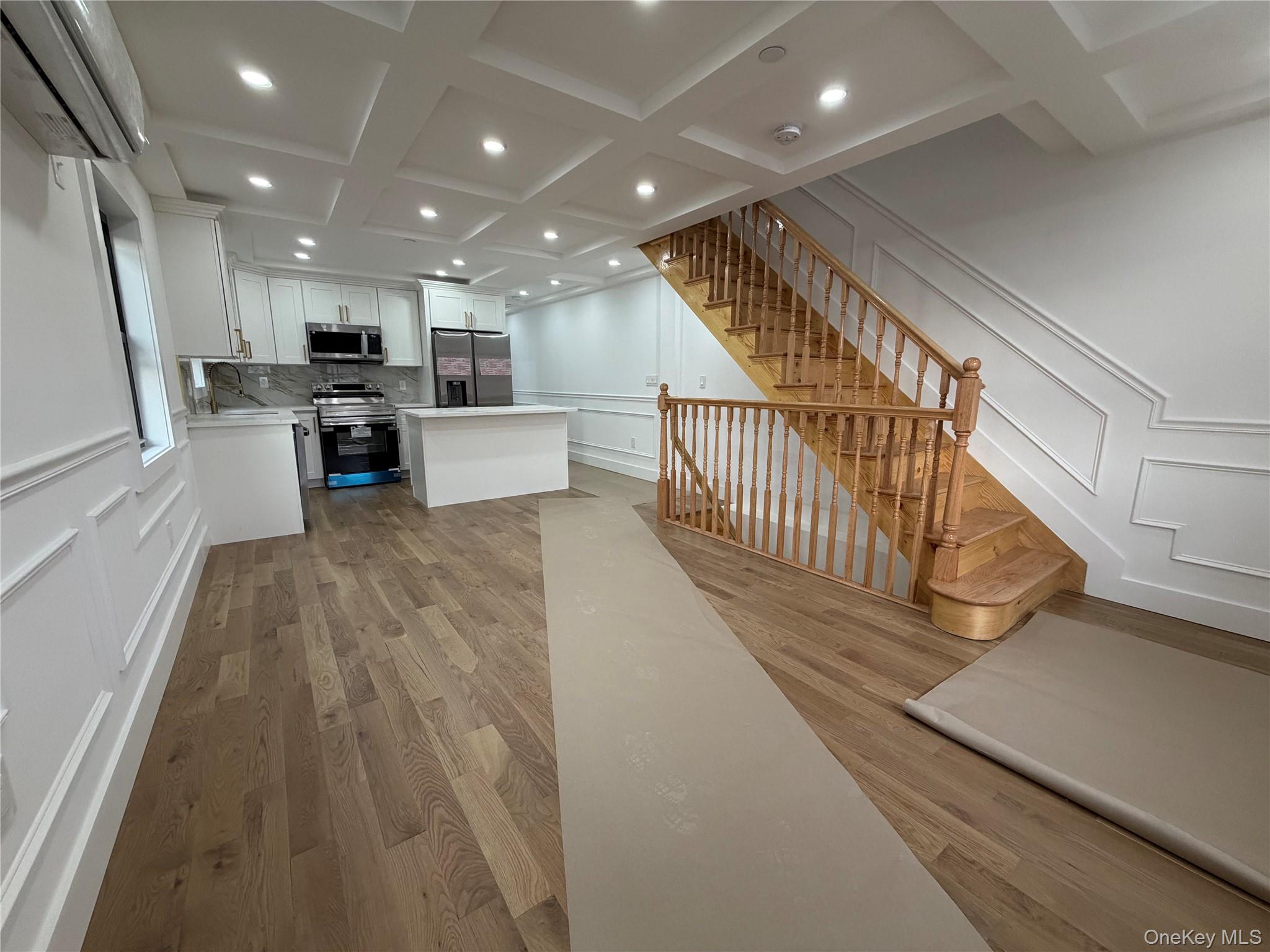 126-22 146th Street Queens, NY 11436 - Photo 8 of 20 a view of a living room and kitchen with furniture wooden floor and windows