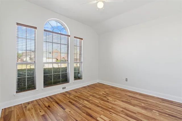 a view of empty room with wooden floor and fan