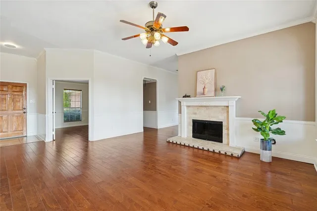 a view of an empty room with wooden floor and a fireplace
