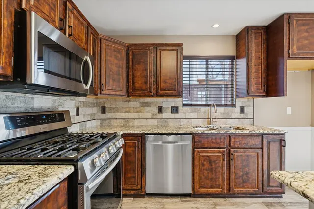 a kitchen with stainless steel appliances granite countertop a stove a sink and a microwave