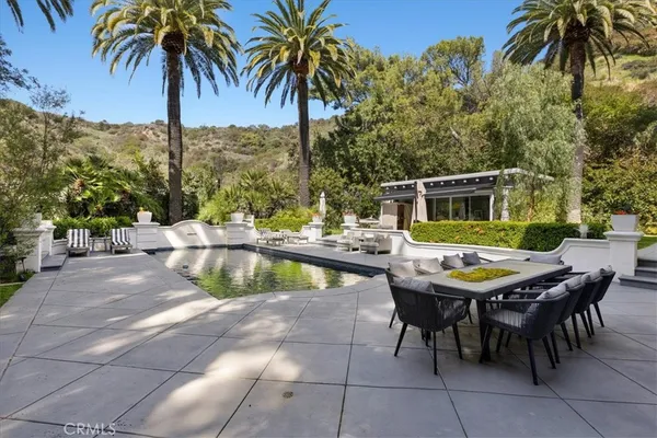 a large kitchen with a large counter top a sink stainless steel appliances and windows