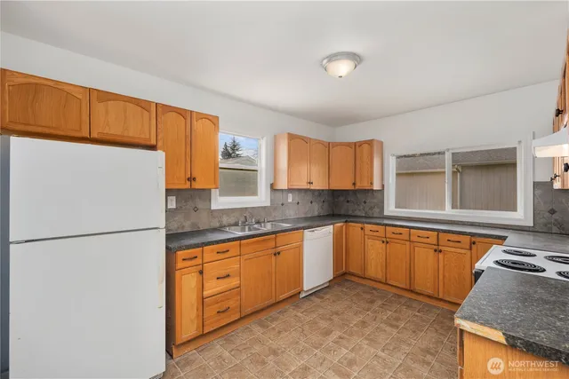 a kitchen with granite countertop a sink stove and refrigerator