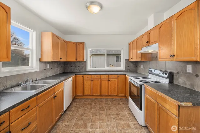 a large kitchen with stainless steel appliances granite countertop a stove a sink dishwasher and a refrigerator